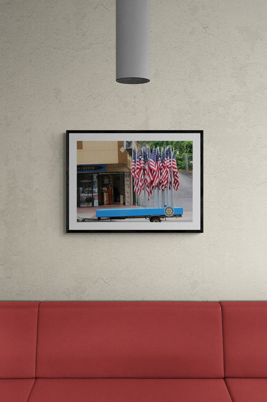Framed photograph of a truck with American flags parked on a wall above a red couch.