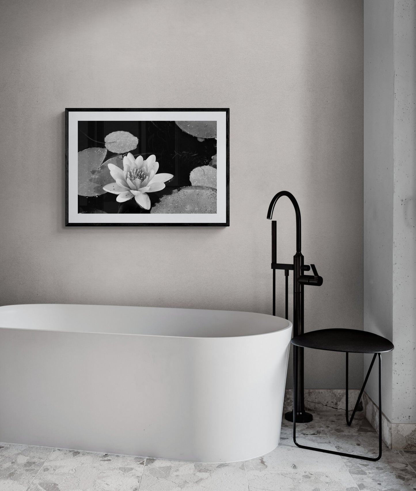 Modern bathroom with a framed black and white water lily print, white bathtub, and black faucet.