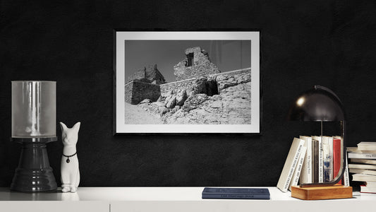 Framed black and white photo of a rocky landscape on a dark wall with decorative items. B/W Ruins on Olive Farm - Portugal, Original Photograph by Kim A. Bailey