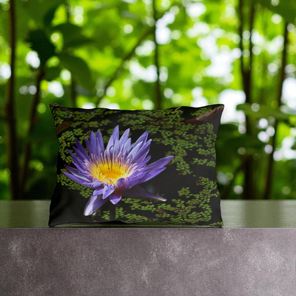 Decorative pillow with a purple flower design on a table with a green blurred background