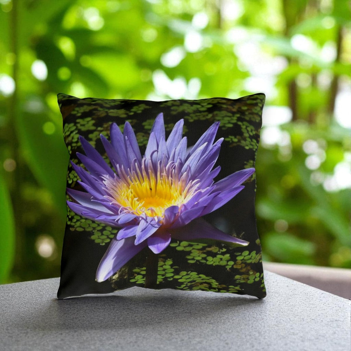 Decorative pillow with a purple flower design on a blurred green background