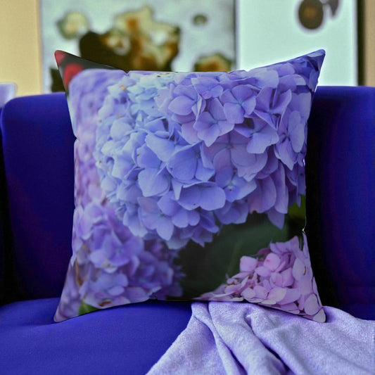 Floral-patterned pillow on a purple couch with a blurred background