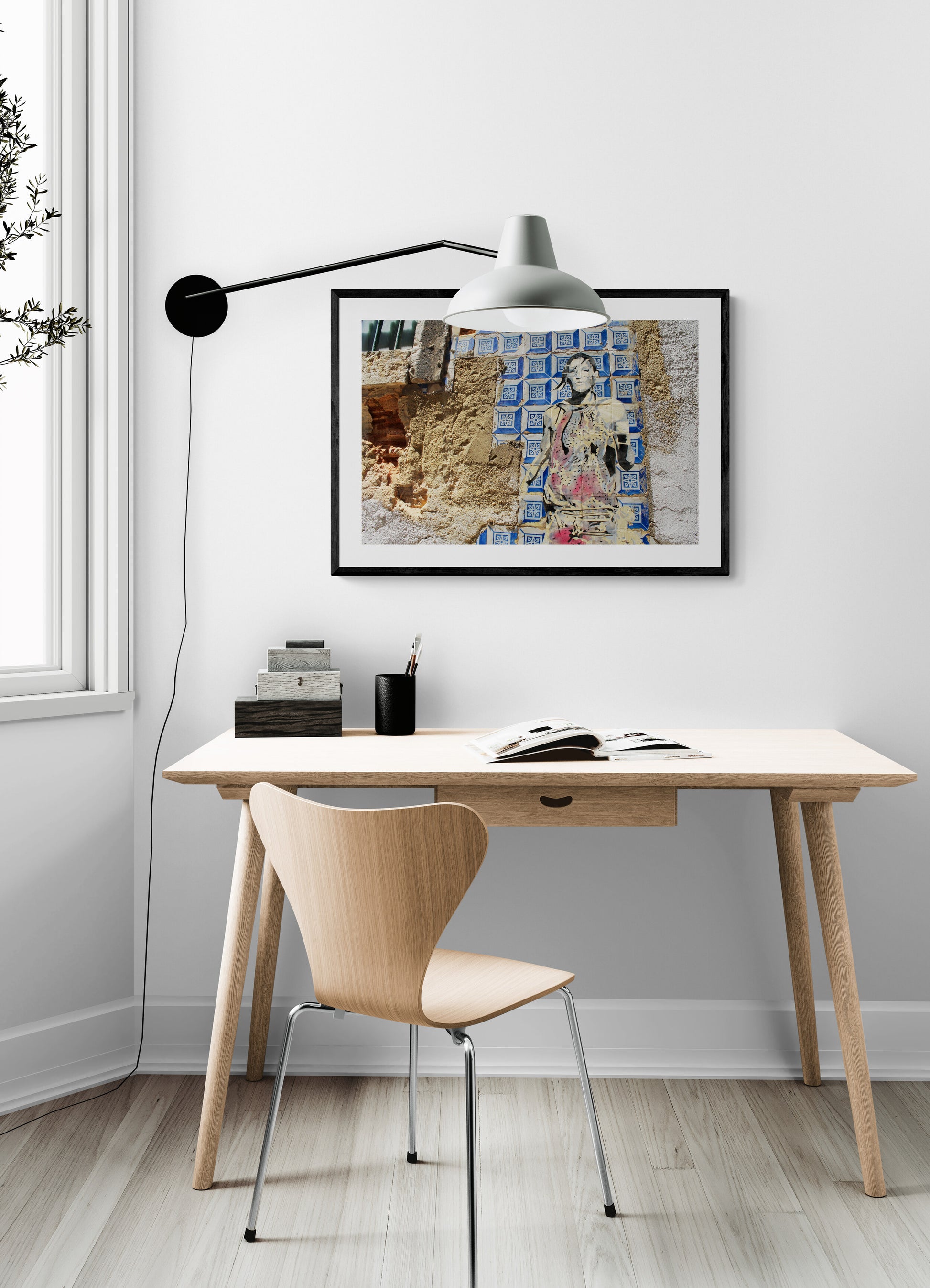 Minimalist desk setup with a lamp, chair, and artwork in a home office.