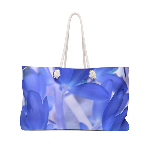 A large tote bag with a blue and white floral print and rope handles.
