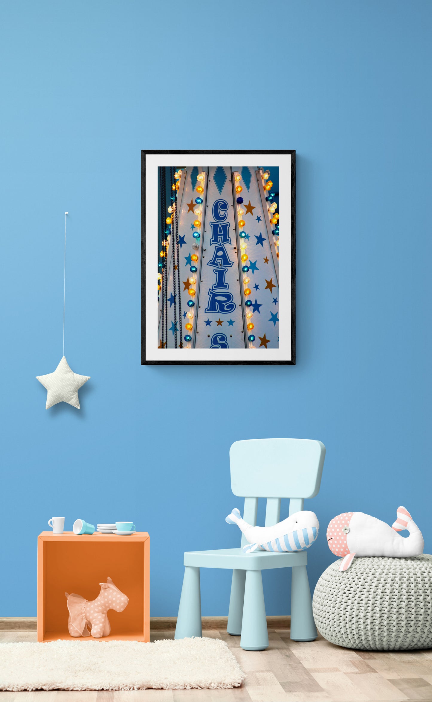 Framed artwork above a blue chair in a room with blue walls.