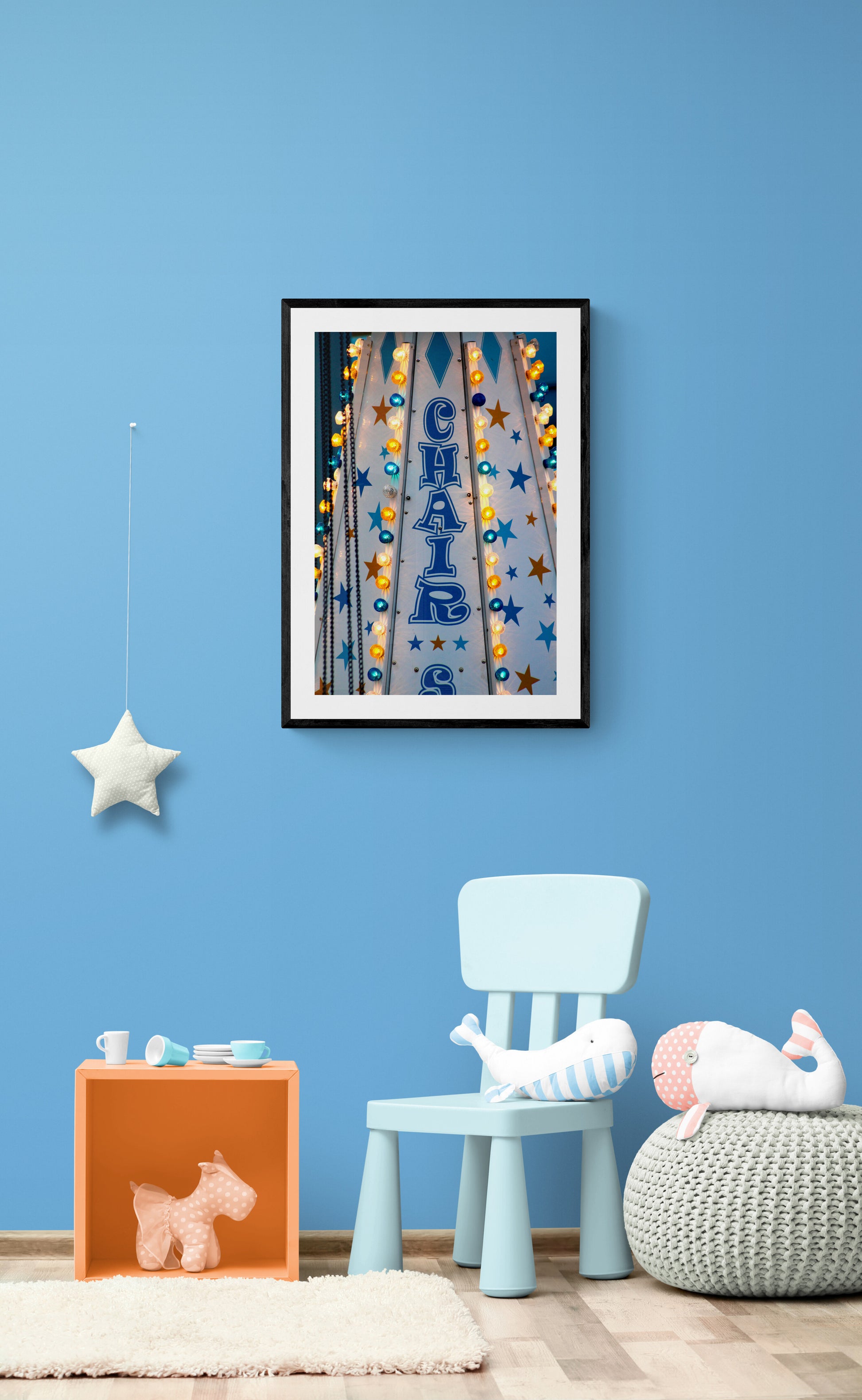 Framed artwork above a blue chair in a room with blue walls.