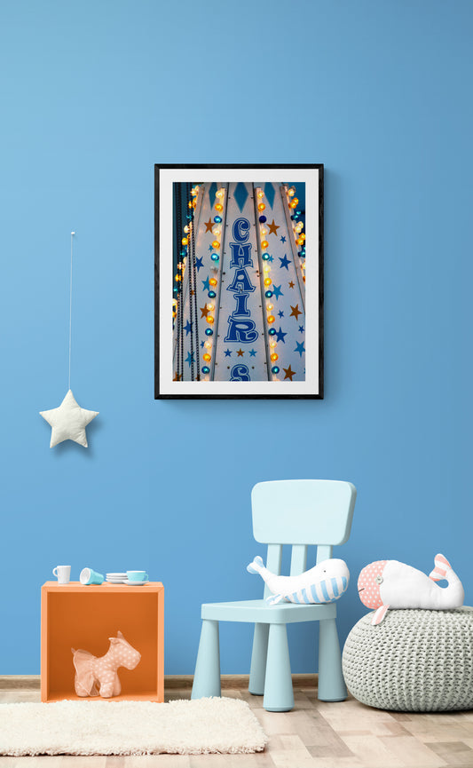 Framed artwork above a blue chair in a room with blue walls.