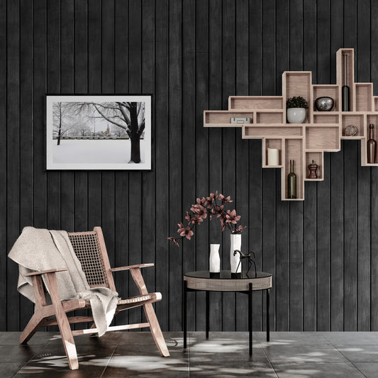 Modern interior with wooden armchair, round table, and wall shelves against a dark paneled wall.