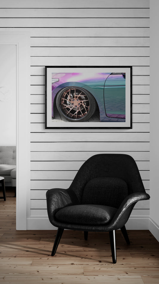 Black armchair in a room with a framed picture of a car on the wall.