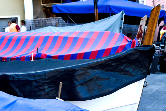A photograph of covered fishing boats with red, white, and blue striped patterns on the tarp, parked on a dock. Covered Boats, Original Photograph by Kim A. Bailey