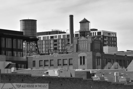 Black and white photograph of an industrial cityscape with several buildings and a water tower prominently visible. Denver Ale, Original Black and White Photograph by Kim A. Bailey