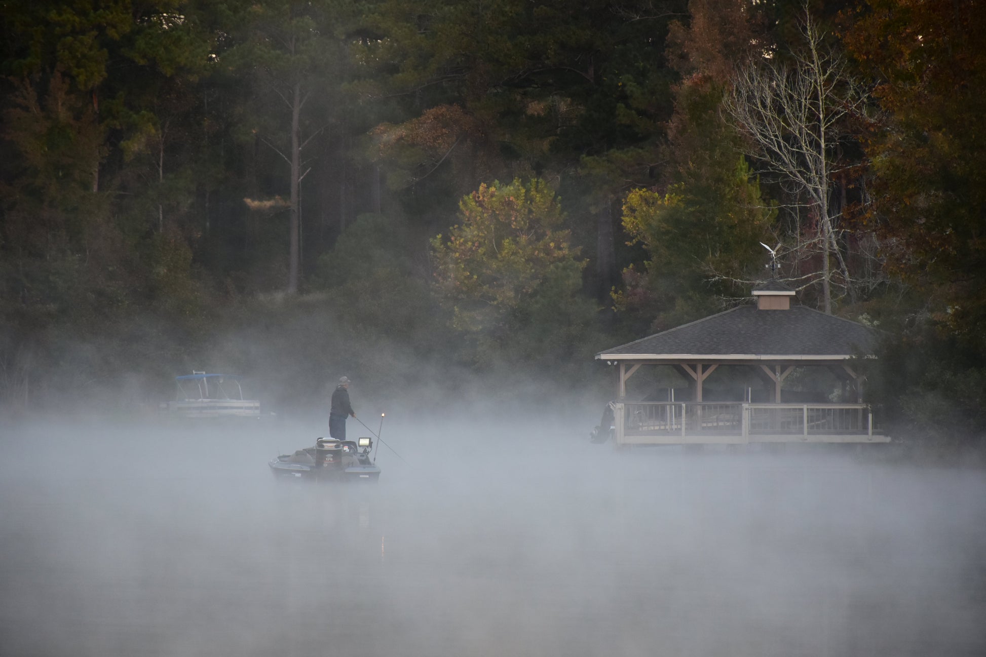 Person on a boat in a foggy lake with a gazebo in the background