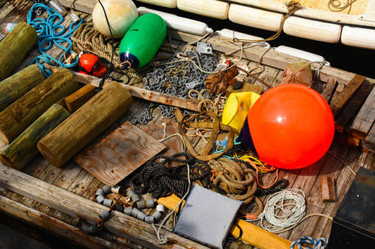 A variety of colorful fishing gear including buoys, ropes, and other equipment laid out on a wooden surface, likely part of a collection displayed on a boat.
