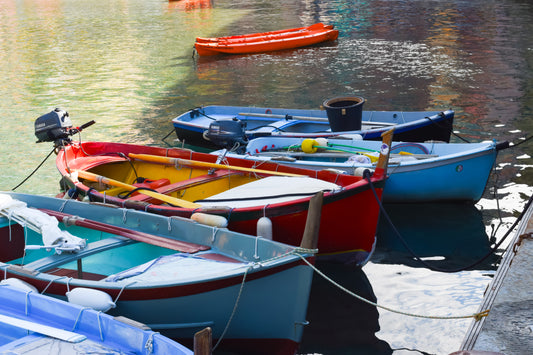 A photograph of colorful fishing boats docked in a bay, with the boats appearing vibrant and the water reflective.