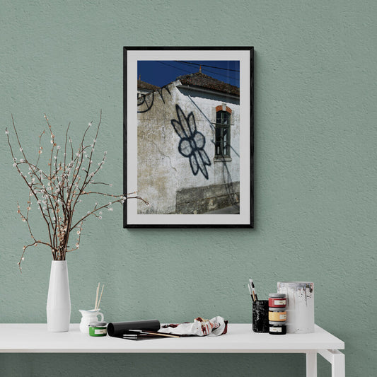 Framed photograph of a building with graffiti on a green wall above a table with art supplies. Flower Shadow - Portugal, Original Photograph by Kim A. Bailey
