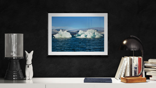 Framed photograph of icebergs in a darkly decorated room with books and lamps.