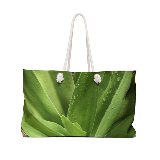 A large tote bag with an abstract green lily plant design, featuring rope handles.