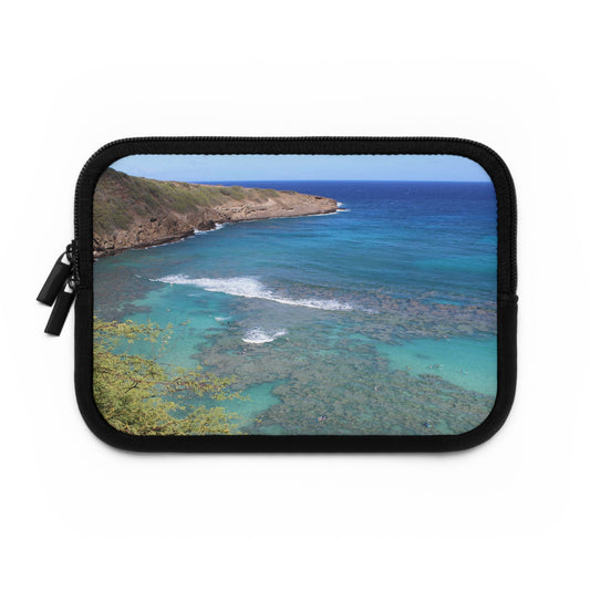 A neoprene laptop or tablet sleeve with a black back and a beach scene photograph printed on the front.