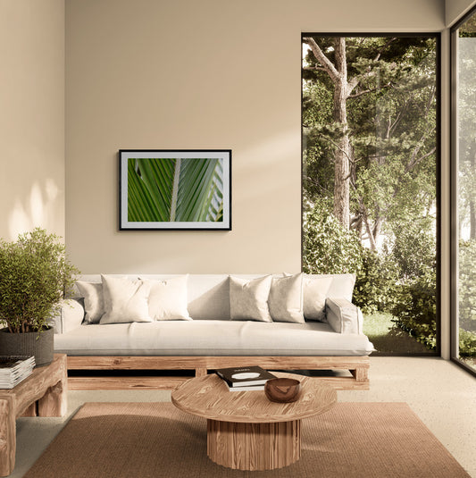 Modern living room with wooden sofa, coffee table, and wall art depicting a leaf.