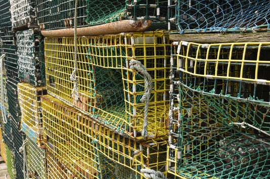 A stack of colorful lobster traps on a wooden dock, with a focus on the vibrant yellow and green cages.