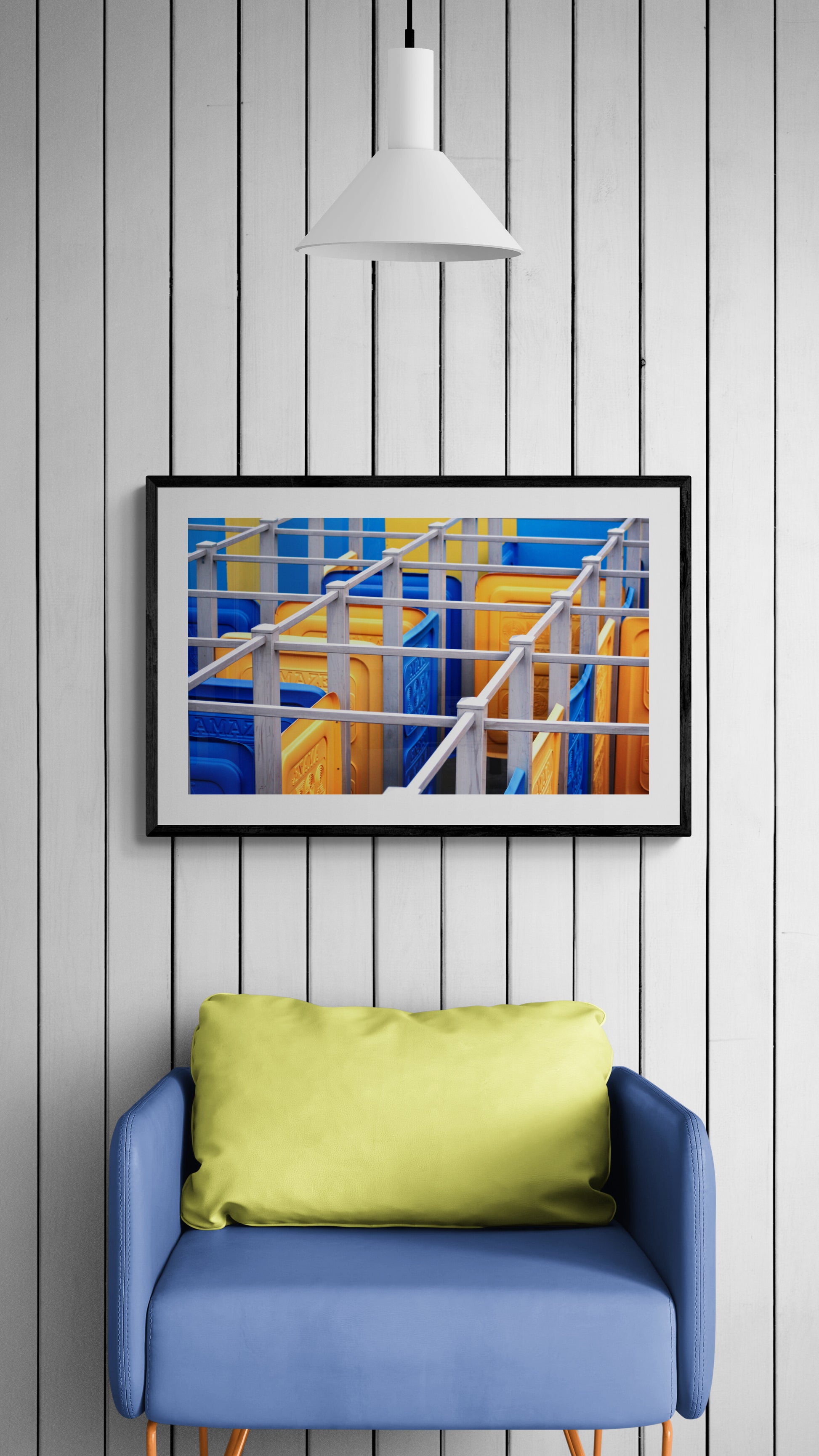 Framed abstract art on a wall above a blue chair with a green pillow.