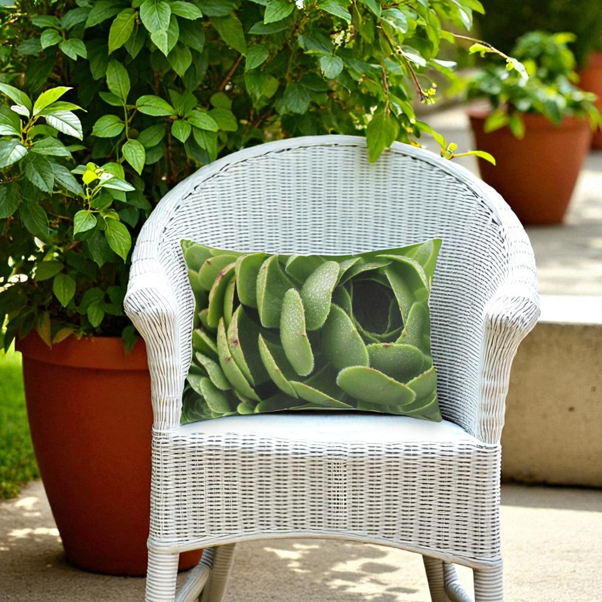 White wicker chair with a green succulent-patterned pillow, surrounded by potted plants.