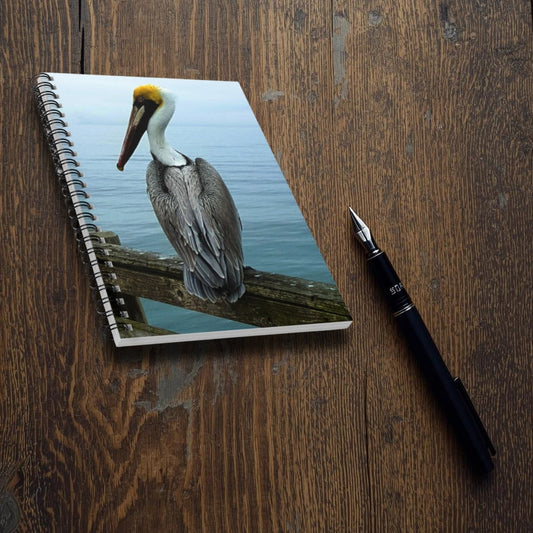 Notebook with a pelican design on a wooden surface next to a fountain pen