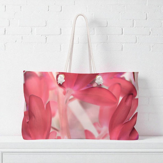 Tote bag with pink floral design on a white brick wall background