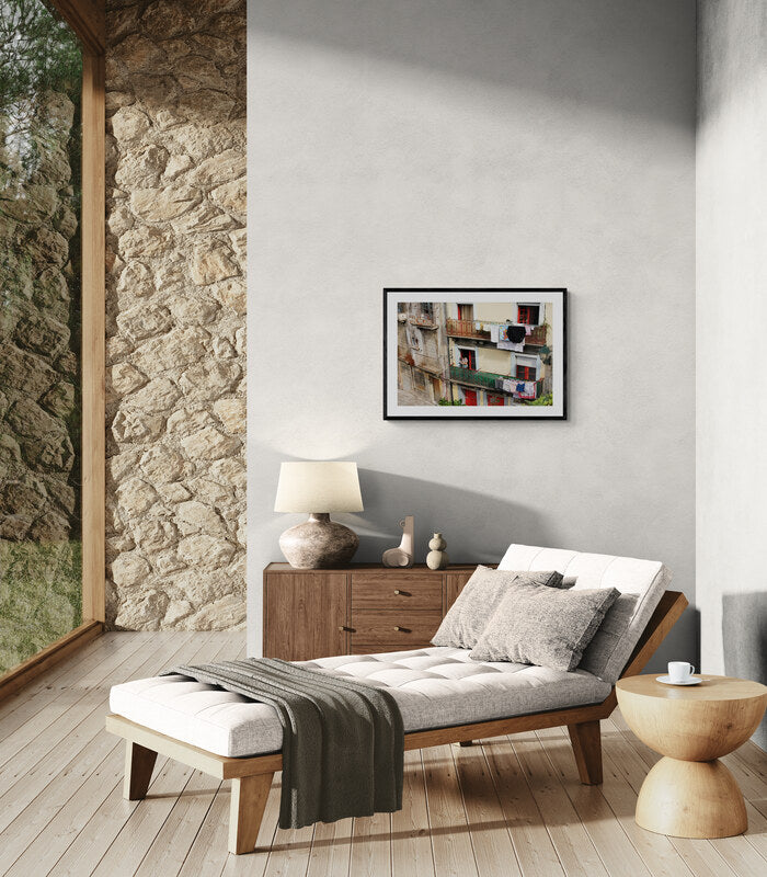 Modern living room with a wooden daybed, stone wall, and artwork. Portuguese Woman Hanging Laundry, Original Photograph by Kim A. Bailey