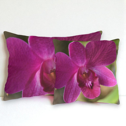 Two pillows with pink orchid design on a white background