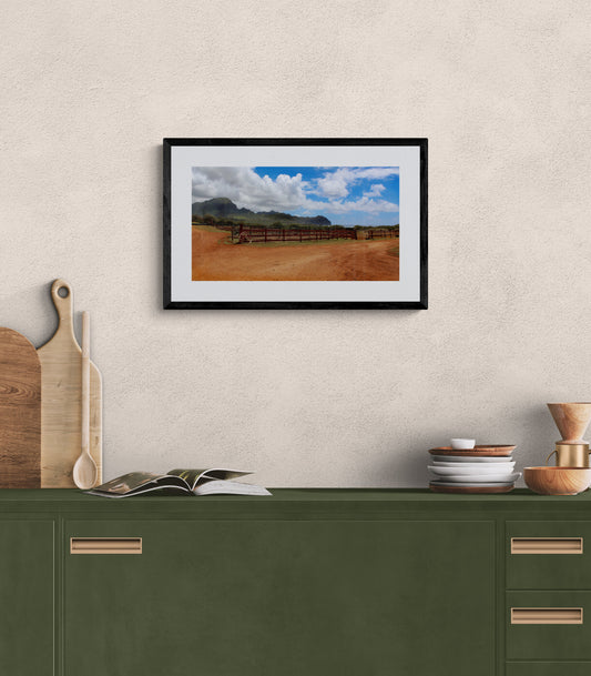 Framed photograph of a horse ranch on a wall above a green cabinet.
