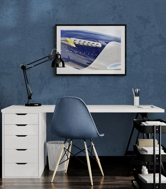 Modern office setup with white desk, blue chair, and framed artwork on a blue wall.
