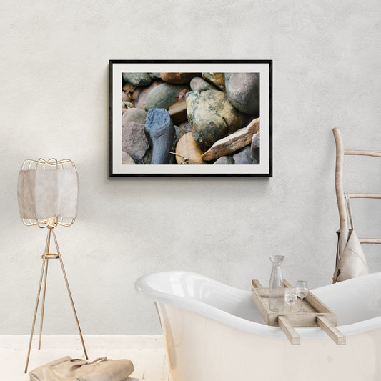 Framed photograph of rocks on a wall above a bathtub.