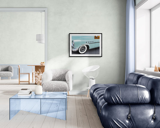 Modern living room with a blue sofa, glass coffee table, and framed picture on the wall.