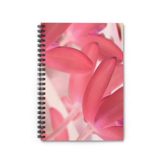 A spiral notebook with a photograph of pink tinted orchids on the cover, featuring ruled lines and a dark grey back cover.