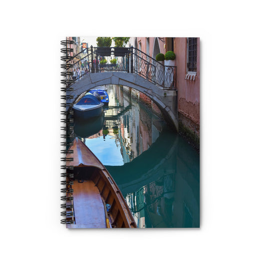 A spiral notebook with a printed cover featuring a photograph of a Venice canal scene, with a bridge, water, and a boat.