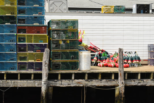 A stack of colorful lobster traps on a weathered wooden dock with a white wall in the background. Stacked Lobster Traps Original Photograph by Kim A. Bailey