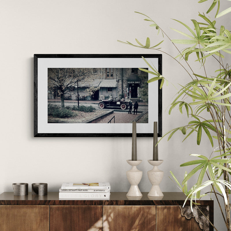 Framed black and white photograph on a wall above a wooden console table with decorative items.