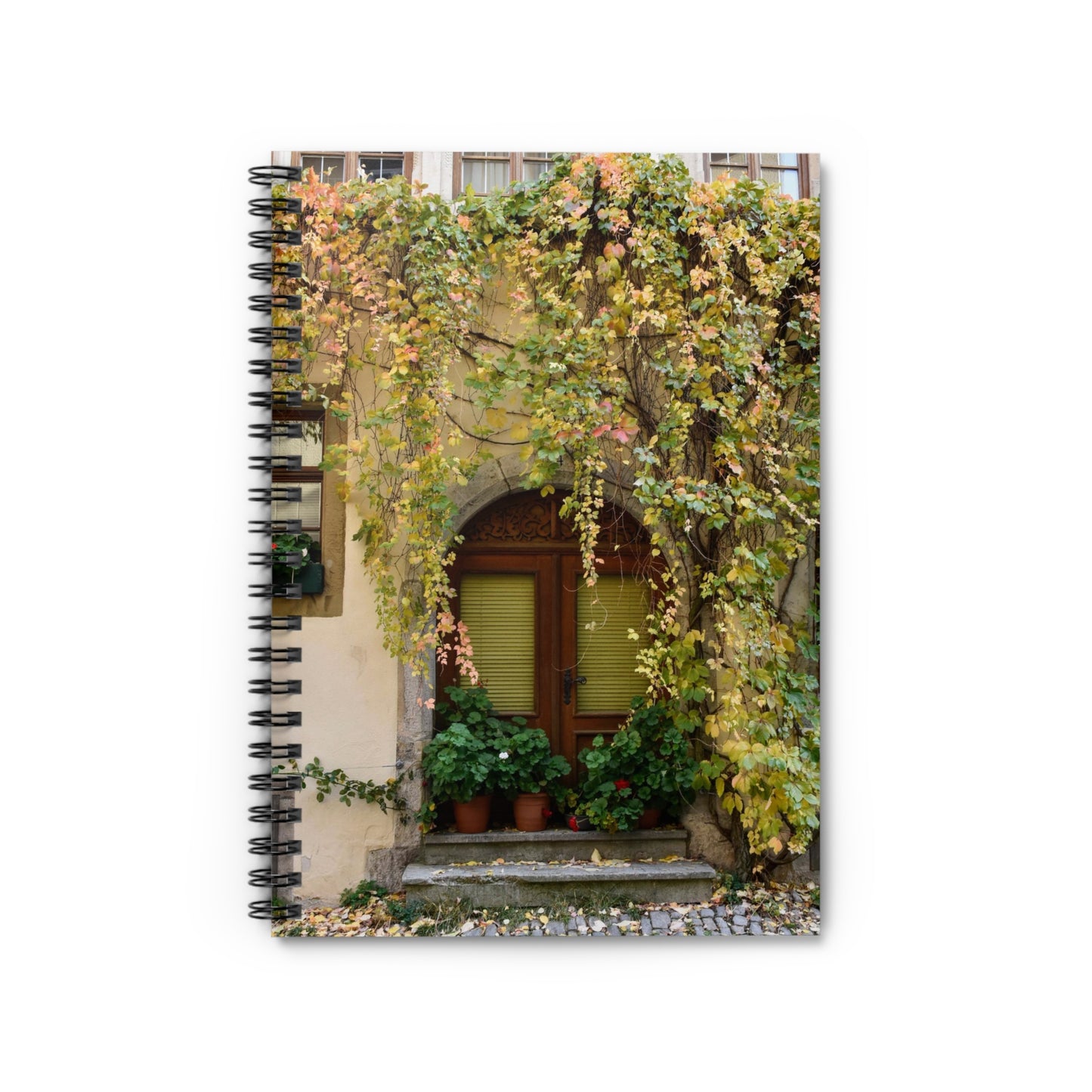 A spiral notebook with a photograph of vines over a door printed on the cover, featuring a dark grey back cover and ruling lines for writing.