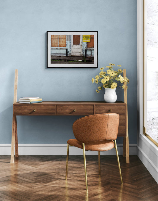 Room with a desk, brown chair, and vase of flowers against a blue wall. A color photograph of a weathered lobster store on a dock, with signs of aging and use, including a yellow sign that reads 'CUSTOMERS ONLY', and a door with visible wood grain and paint wear. Weathered Lobster Store Original Photograph by Kim A. Bailey