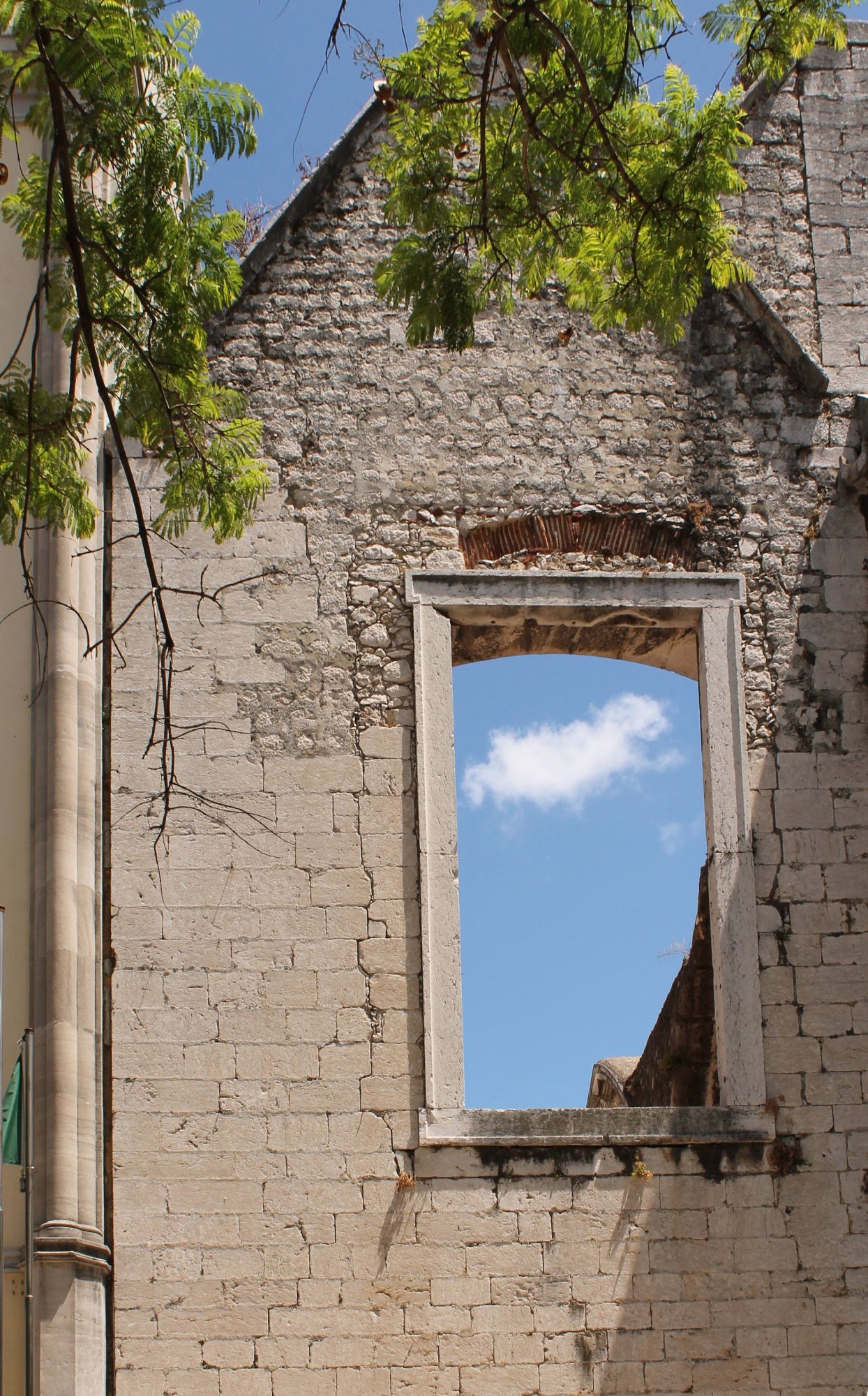 An original photograph capturing a brick wall with a rectangular window opening, through which a bright blue sky is visible. Window to Sky, Original Photograph by Kim A. Bailey