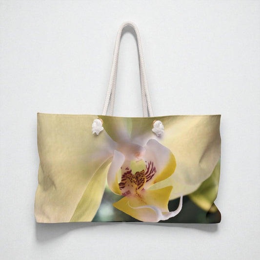 Tote bag with a floral design featuring a white and yellow orchid on a light gray background
