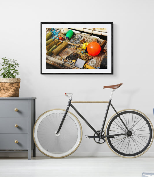 Framed photograph of a wooden table with fruits and a bicycle in a room.