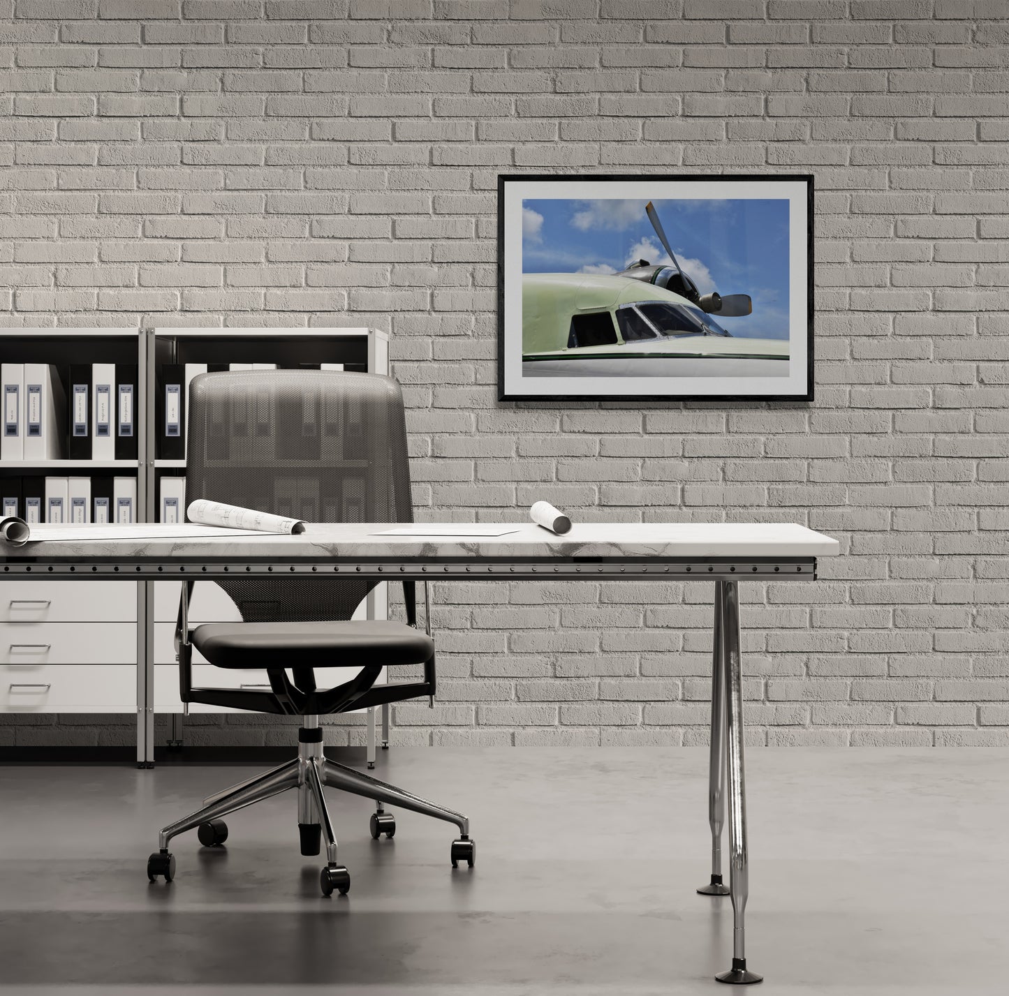 Modern office setup with a desk, chair, and framed picture of an Albatross Plane on a brick wall.
