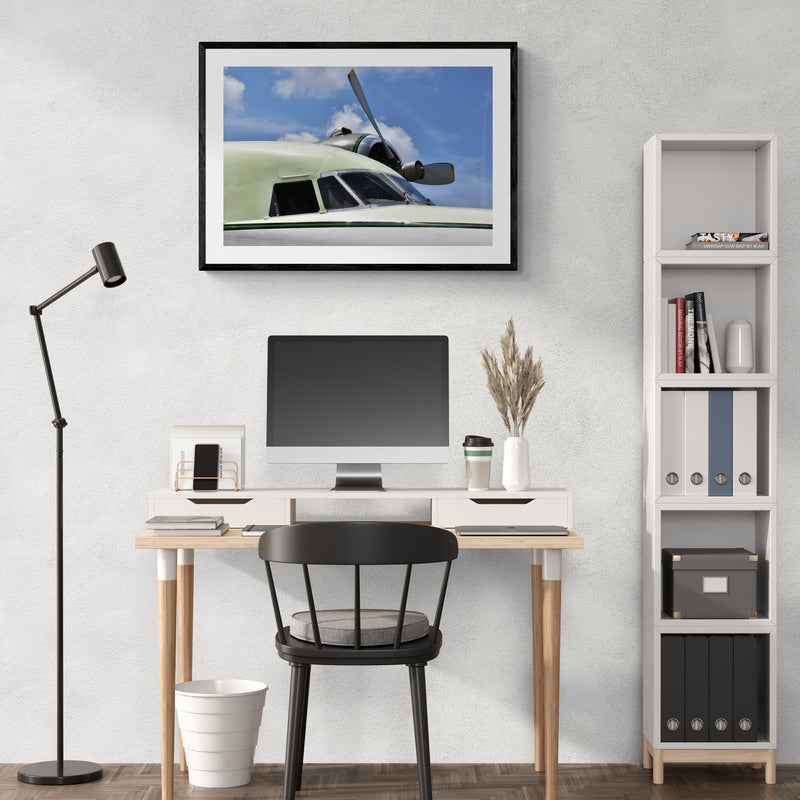 Modern home office with desk, chair, computer monitor, and framed picture of an airplane.