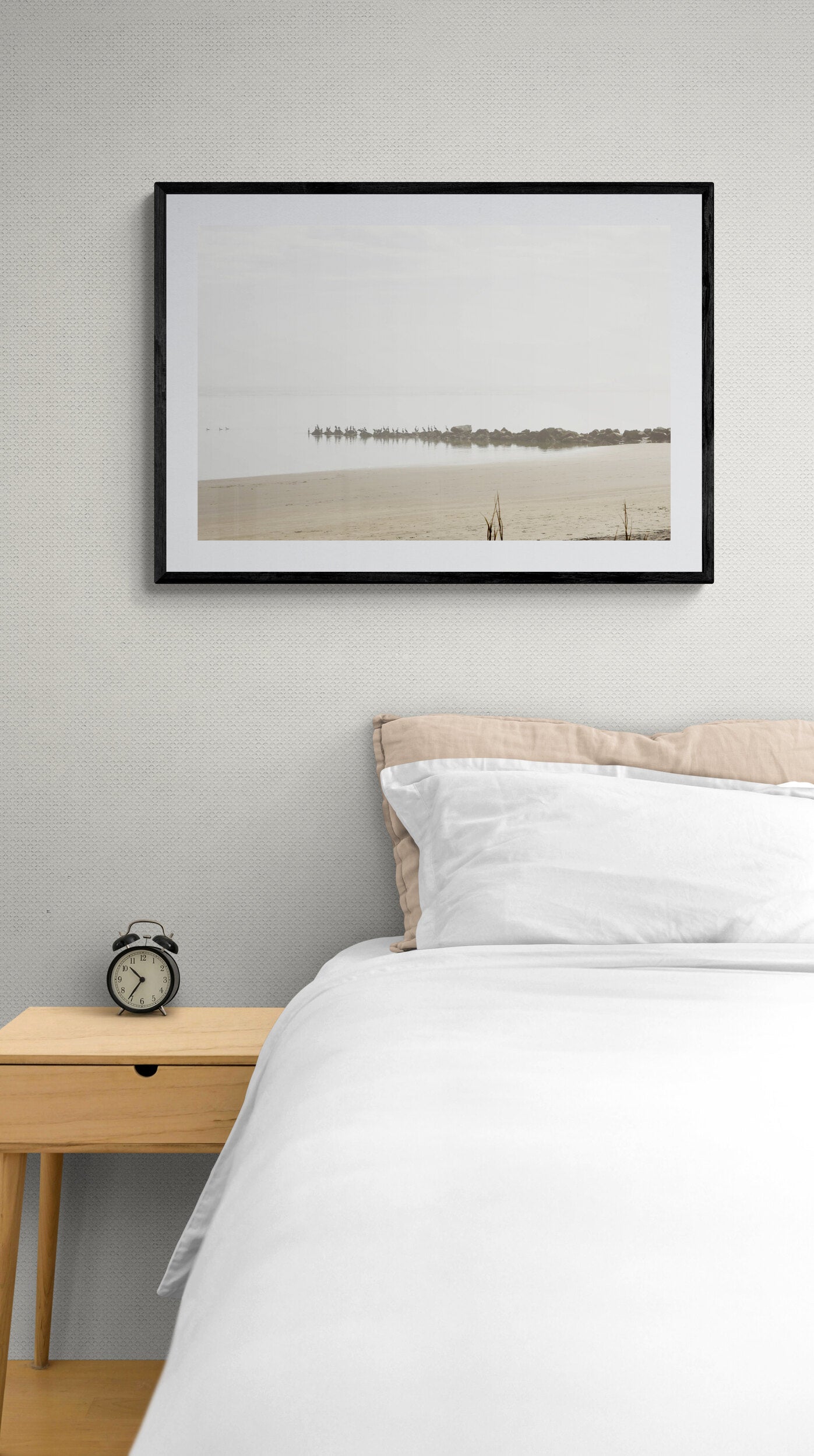 Framed photograph of a beach scene above a bed in a bedroom.