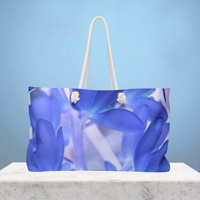 Blue floral-patterned bag with white handles on a light blue background