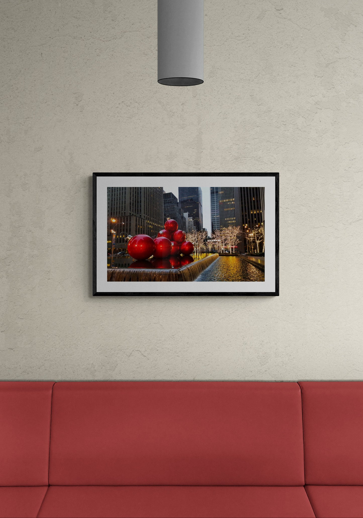 Framed artwork of red sculptures in a cityscape on a wall above a red sofa.