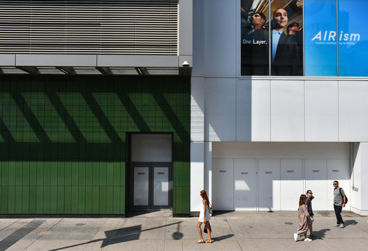 Urban Photograph in big blocks of white, grey, blue, and green colors. People walking through the scene add scale.