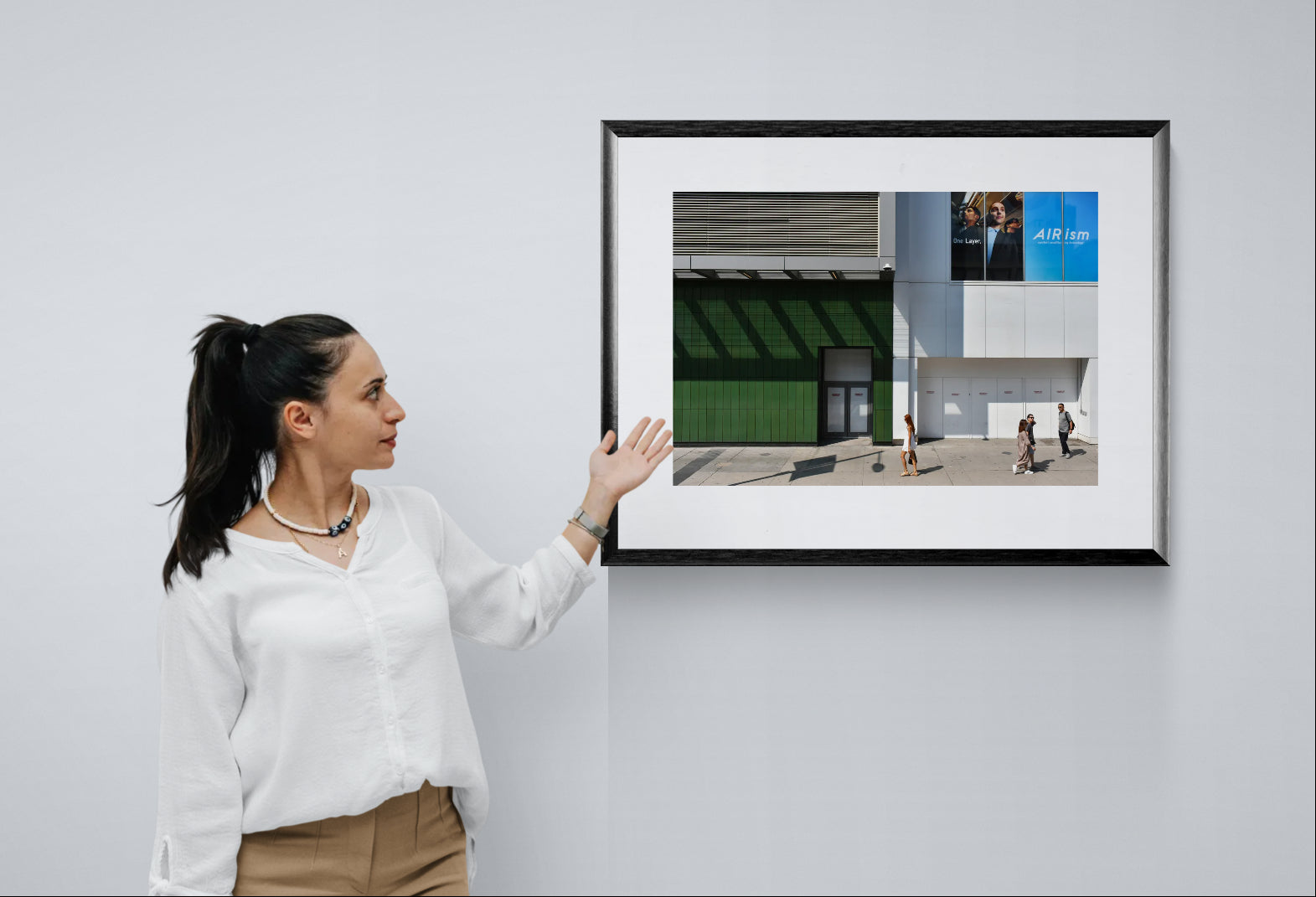 Urban Photograph in big blocks of white, grey, blue, and green colors. People walking through the scene add scale. Framed photograph hanging on a gallery wall.
